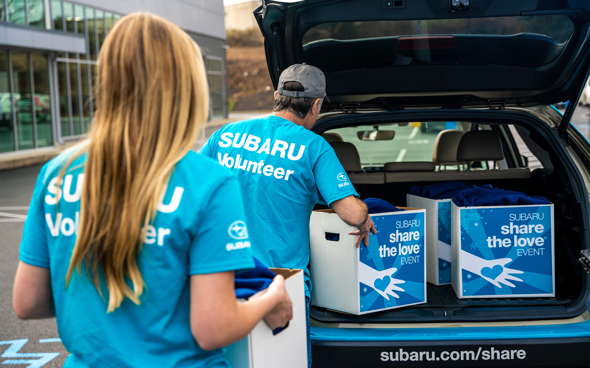 Subaru volunteers loading Share the Love Event boxes into a car